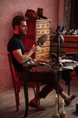 gorgeous guy hitting the shoe with a hammer, side view full length photo