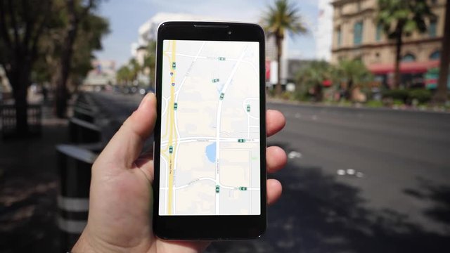A man uses his smartphone to observe ride sharing traffic patterns on an interactive map in Las Vegas.	 	