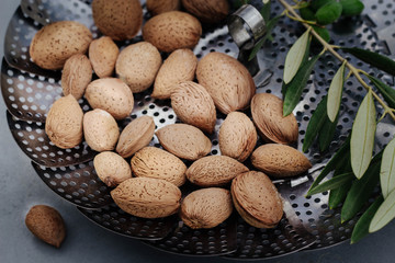 fresh, tasty almonds in shell and olive branches with olives fruits on a tray