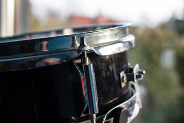 The drum set stands at the window and is lit by the rays of the spring sun and daylight, against a blurred background. Hobby and passion to music.