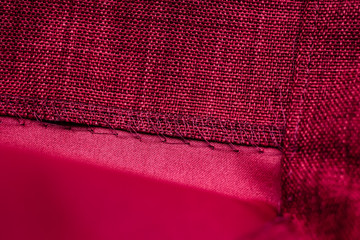 Overlock seam on a red curtain of durable fabric. Macro photo.