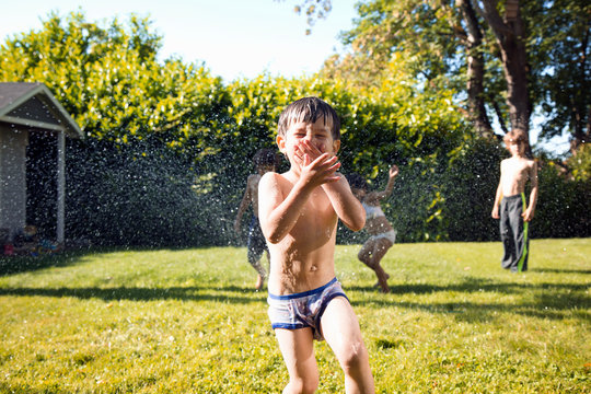 Boys playing in sprinkler 