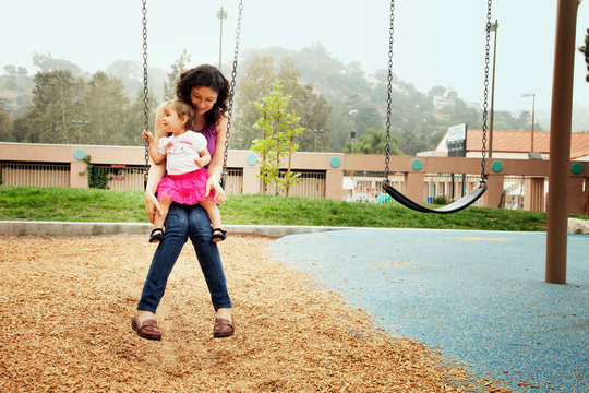 Mother playing on swings with daughter
