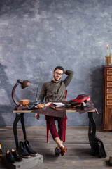 relaxed young gorgeous shoe designer posing to the camera, full length photo, male selling shoes