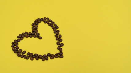 Heart of coffee beans on the left on a yellow background