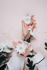 Creative and fashion art skin care of hands and white flowers in hand of women. Female hand with white flowers on pink background. Cosmetics for hands anti wrinkle. Flat lay, top view, copy space