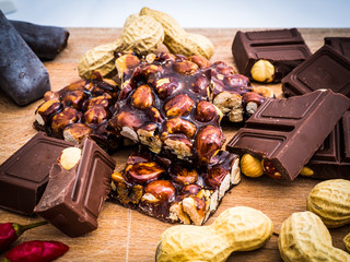 delicious chocolate and Italian hazelnut nougat, cut into pieces, for a sea of sweetness, in the background other nougats and chillies. Taken up close, with blurred background