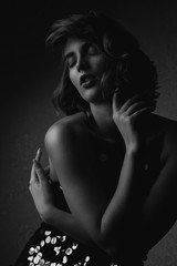 Black and white portrait of seductive brunette woman wearing sparkling dress posing with dramatic light