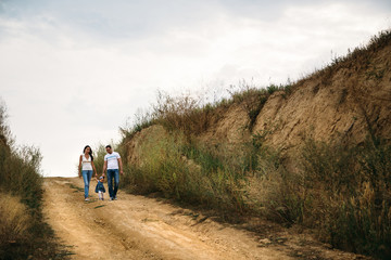 Young family with a small kid walking on the country road, outdoors background