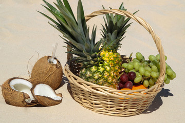 Fresh fruits in the basket on white sand beach