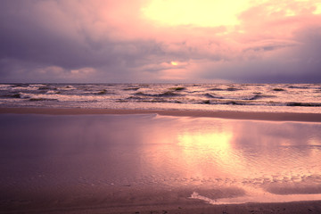 Sunset over the sea with a dramatic cloudy sky. Stormy weather. Waves on the sea. Twilight time