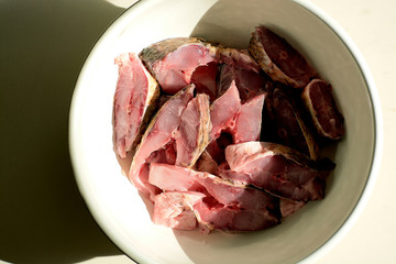 Fresh carp fish fillets slices in the white dish. natural sun light. hard shadows.