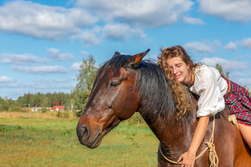 Girl posing sitting on a horse and hugs her neck. Concept of love for animals