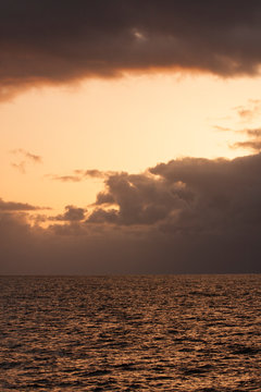 Sky, sunset, ocean, sea, water, ocean waves, clouds, glowing light, colorful, calming, vertical image