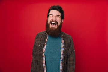 A close up portrait of young happy cheerful young man in checkered shirt in front of redbackground