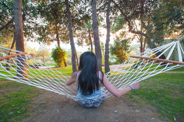 girl in hammock swinging while admiring the green nature