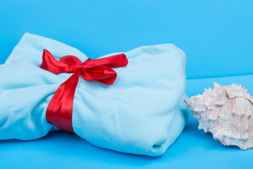 Blue fabric with a red ribbon. gift with ribbon. Shell on the fabric. Gift on a blue background