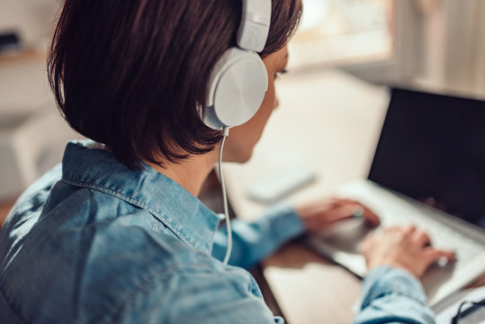 Woman using laptop and listening music on a headphones