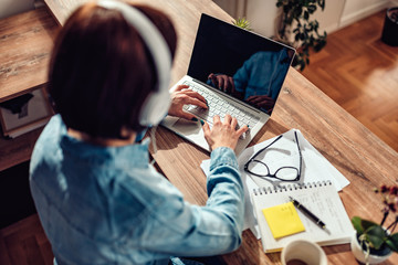 Woman using laptop and listening music on a headphones