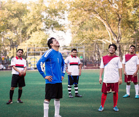 Soccer team standing in playing field and laughing 