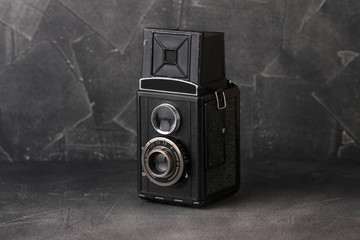The old medium-format scaling film camera on grey cement background. TLR film camera.