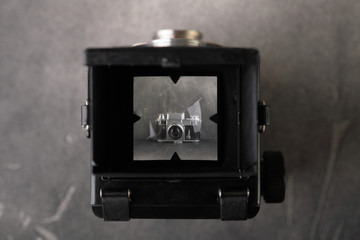 The old medium-format scaling film camera on grey cement background. TLR film camera.