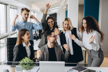 Male worker share good news with multiracial colleagues in shared workplace, diverse employees scream with happiness excited with corporate success or goal achievement, team celebrating win