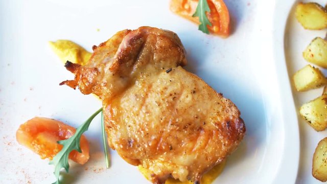 Nice chicken grill meat on white plate with sauce, poteto and tomato. Close up 4k food footage.
