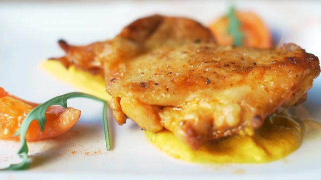 Nice chicken grill meat on white plate with sauce, poteto and tomato. Close up 4k food footage.