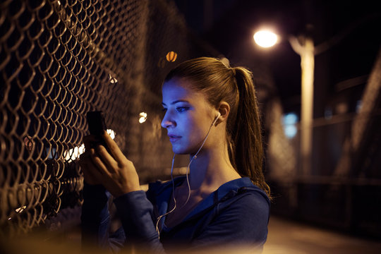 Young woman using mobile phone on bridge at night 