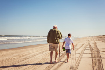 Grandfather and grandson (8-9) on beach by sea 
