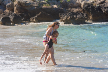 Mother with kid play with water, runing on the beach