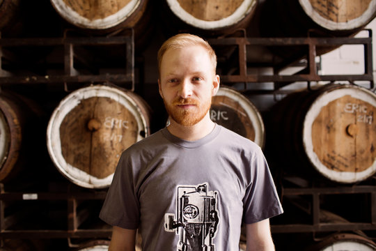 Portrait of man standing in front of rack with barrels 
