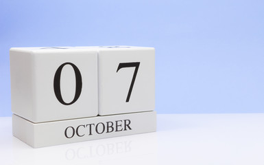 October 07st. Day 7 of month, daily calendar on white table with reflection, with light blue background. Autumn time, empty space for text