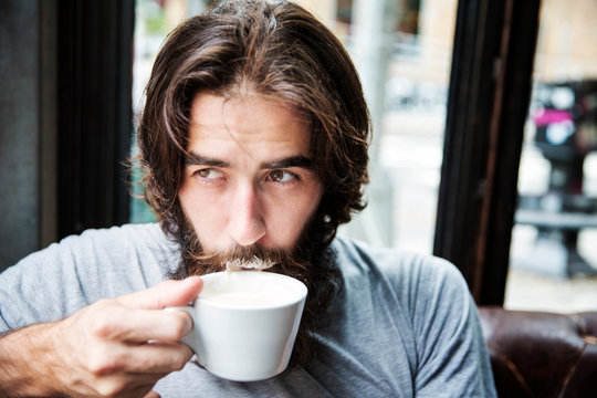 Bearded Man Drinking Coffee In Bar Milk On Mustache 