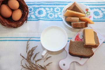 Country breakfast, milk and cereal bread, slices of cheese and fresh eggs in a basket, healthy and healthy food