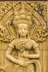 An Apsara dancing carved on the sandstone wall background. Apsara is a female spirit of the clouds and waters in Hindu culture. Her figure prominently in the sculpture, dance, literature and painting.