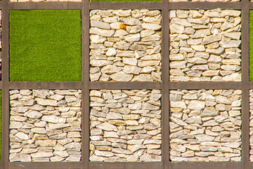 Abstract river pebble stone wall background with green grass frame. Gravel wall background and green grass square shape for background. Square frame wall background with river pebble and green grass.