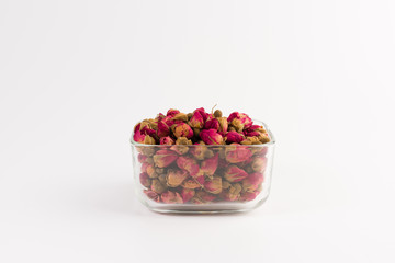 tea rose buds in a glass drinking bowl  isolated on white  background