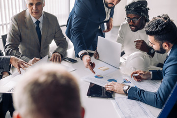 Multiracial group of male experts analyzing business resuls , close up of team with smartphones and...