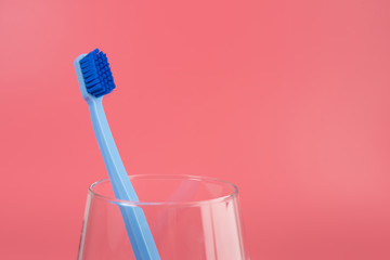 Cup with toothbrush on table against color background. Dental care