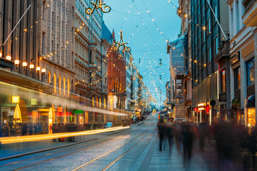 Helsinki, Finland. Tram Departs From Stop On Aleksanterinkatu Street. Night Evening Christmas Xmas New Year Festive Illumination On Street. Beautiful Street Decorations During Winter Holidays