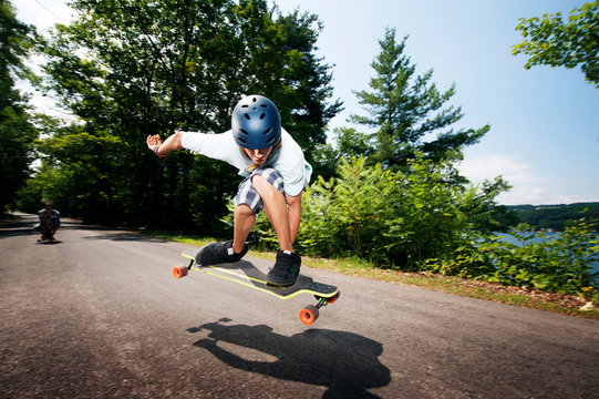 Teenage boy (14-15) jumping on longboard 
