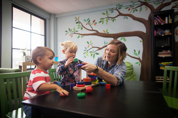 Female teacher playing with kids (2-3,  12-17 months) in preschool 