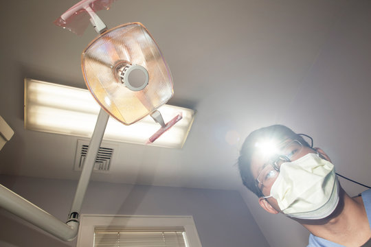 Dentist in surgical mask seen from patient point of view 