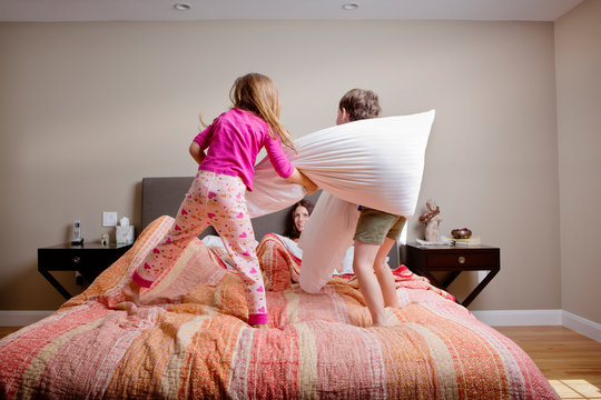 Family pillow fighting in bedroom 