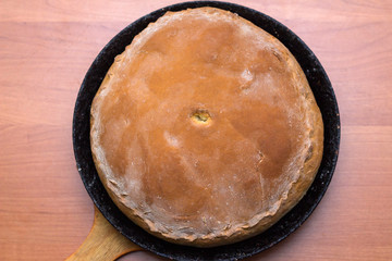 Kurnik, Russian meat pie. A traditional dish of dough lies in a black pan on the table. Meat pie. Top view © PAVEL GERASIMENKO