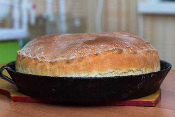 Kurnik, Russian meat pie. A traditional home-made pastry dish lies in a black pan on the table. © PAVEL GERASIMENKO