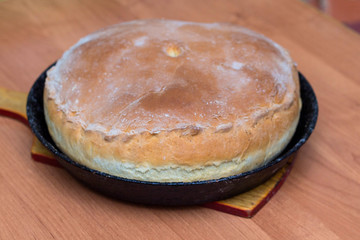 Kurnik, Russian meat pie. A traditional dish of dough lies in a black pan on the table. © PAVEL GERASIMENKO