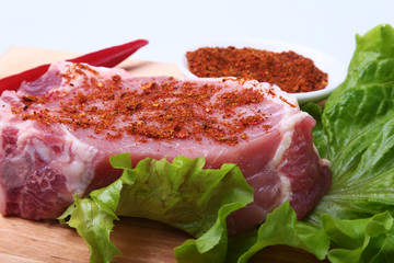 Raw pork steak with herbs, chili pepper and spices on cutting board. Ready for bbq.
